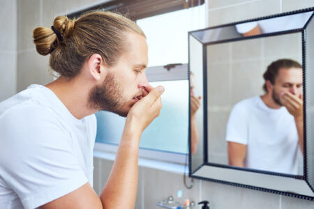 Man with bad breath in front of a mirror.