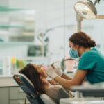 Female dentist examining young woman's teeth