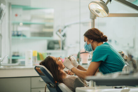 Female dentist examining young woman's teeth